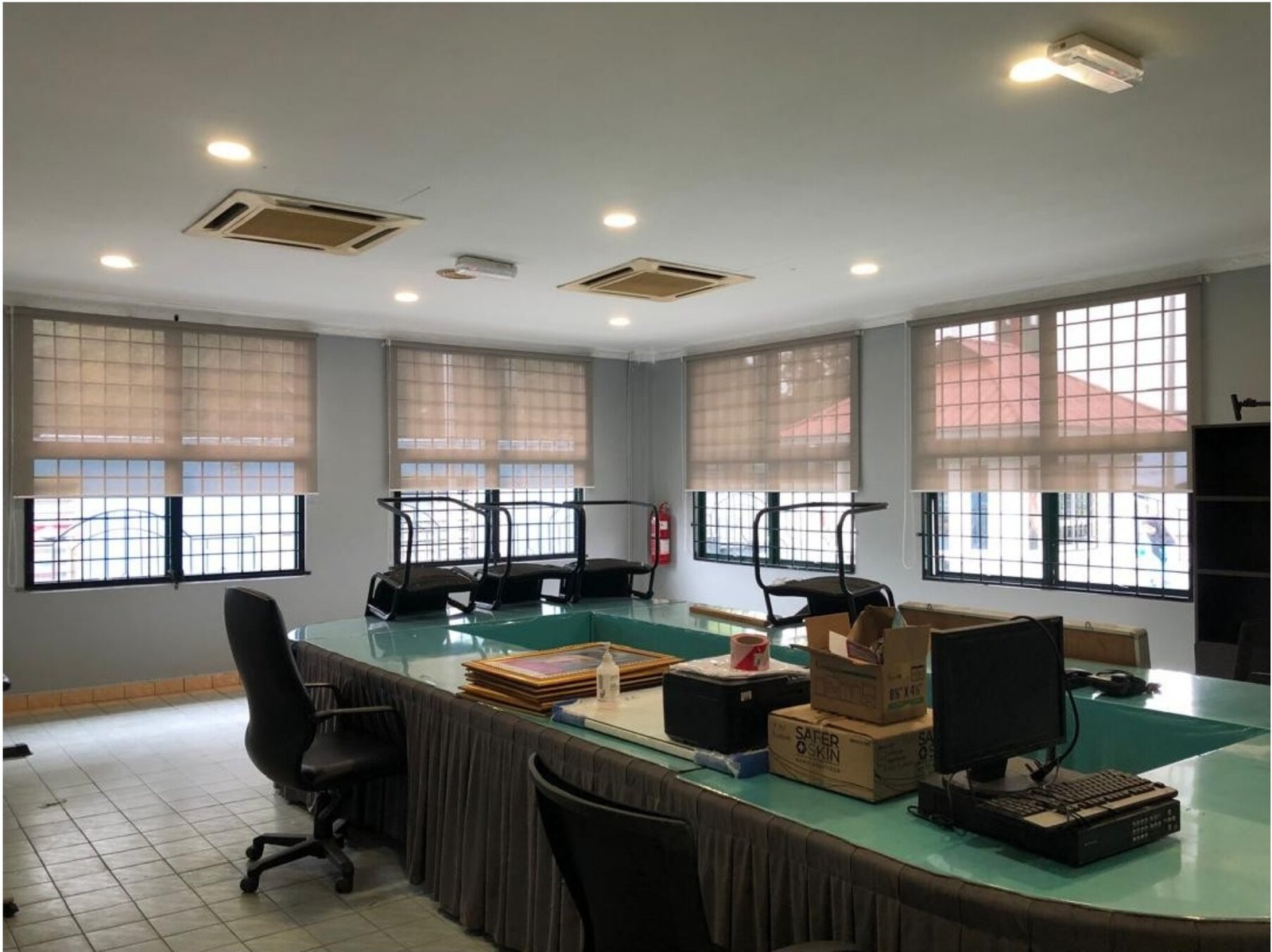 Sunscreen roller blinds fitted across a Malaysian office with U-shaped desk