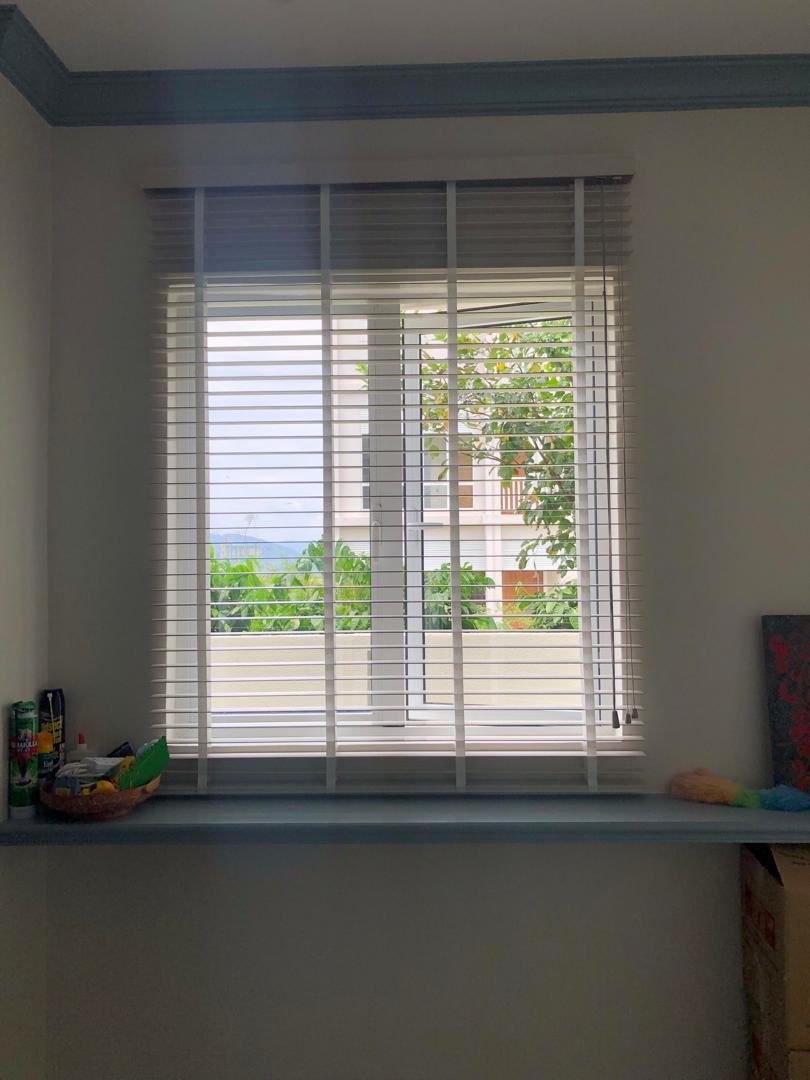 White venetian blinds tilted open in a Malaysian bay-window bedroom
